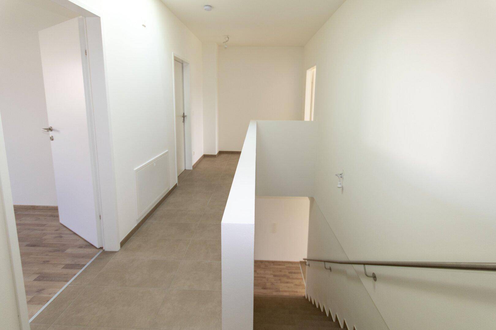 Heller Flur im Obergeschoss mit Fliesenboden und Zugang zu weiteren Räumen.