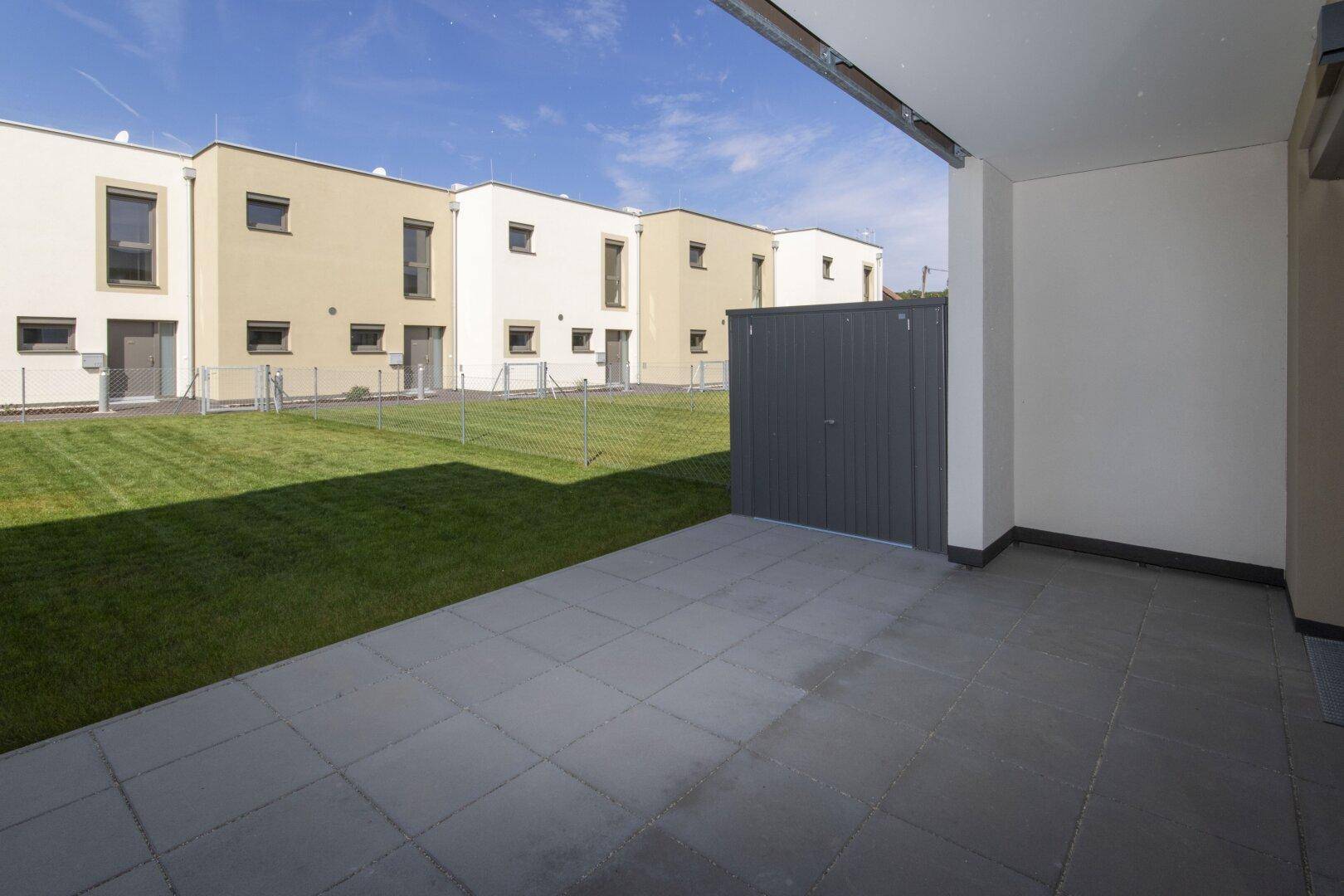 Geräumige Terrasse mit Zugang zum Garten und Blick auf die umliegenden Reihenhäuser.