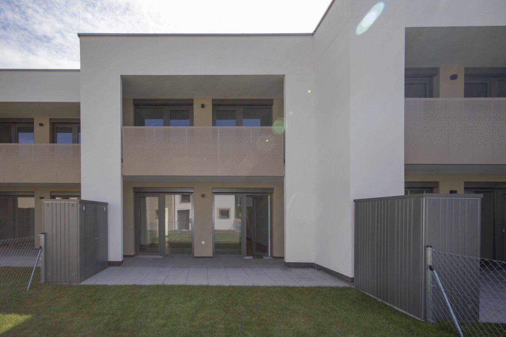 Rückansicht moderner Reihenhäuser mit Terrassen, Balkonen und privaten Gärten.
