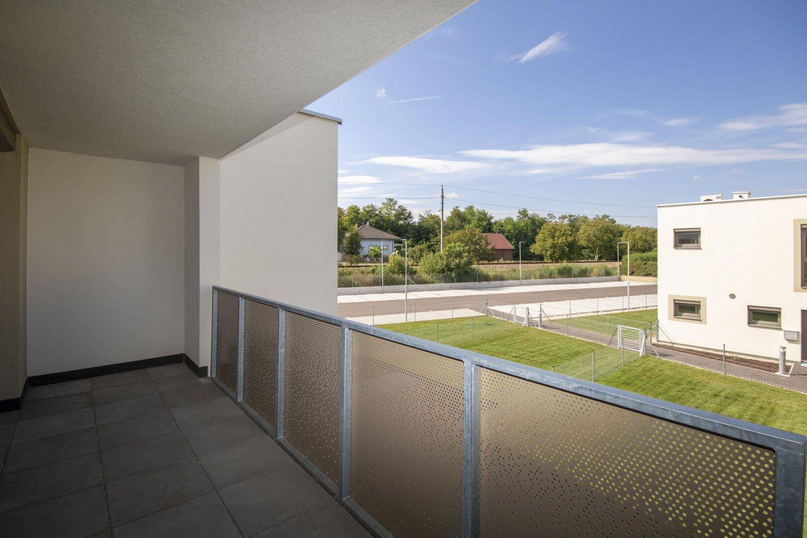 Moderner Balkon mit Metallgeländer und weitem Blick auf die Umgebung und Grünflächen.