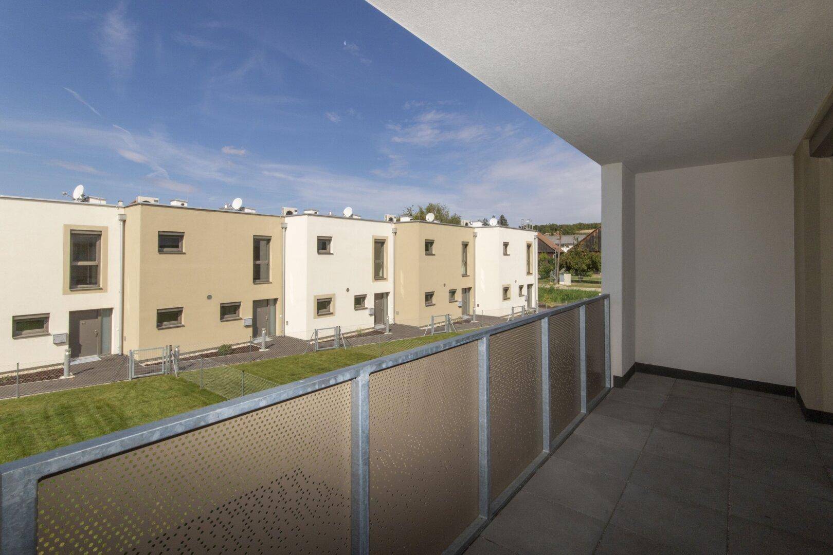 Heller Balkon mit Blick auf die Reihenhäuser und die umliegende Landschaft.
