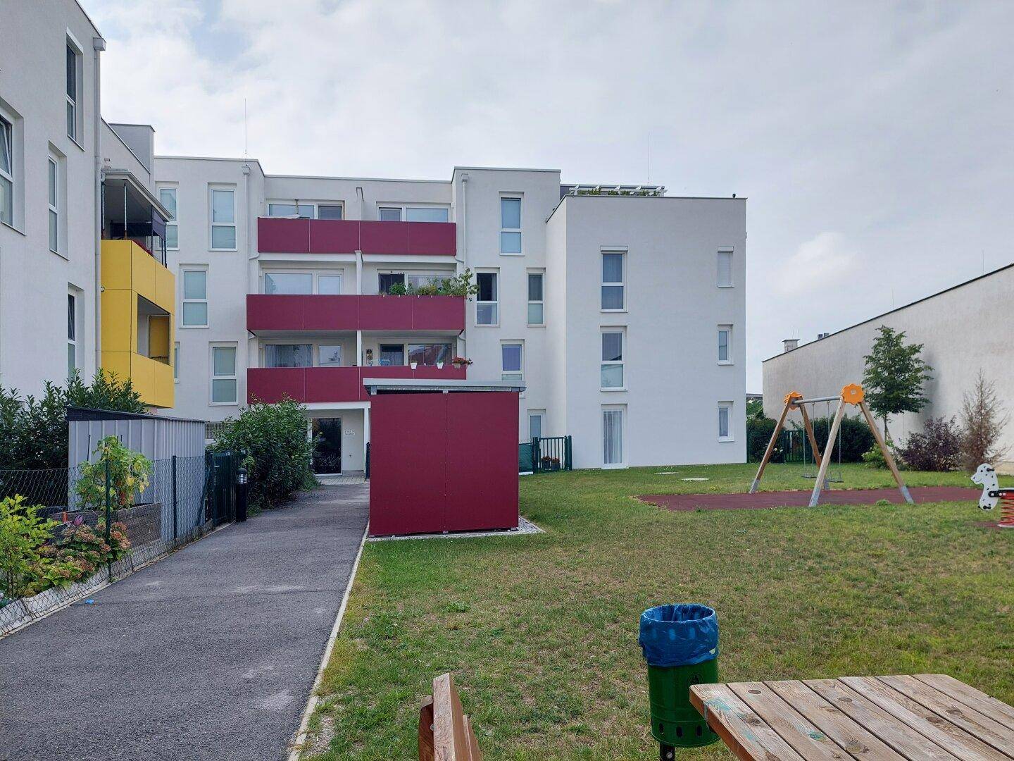 Moderne Wohnanlage mit Gemeinschaftsgarten und Kinderspielplatz im Freien.