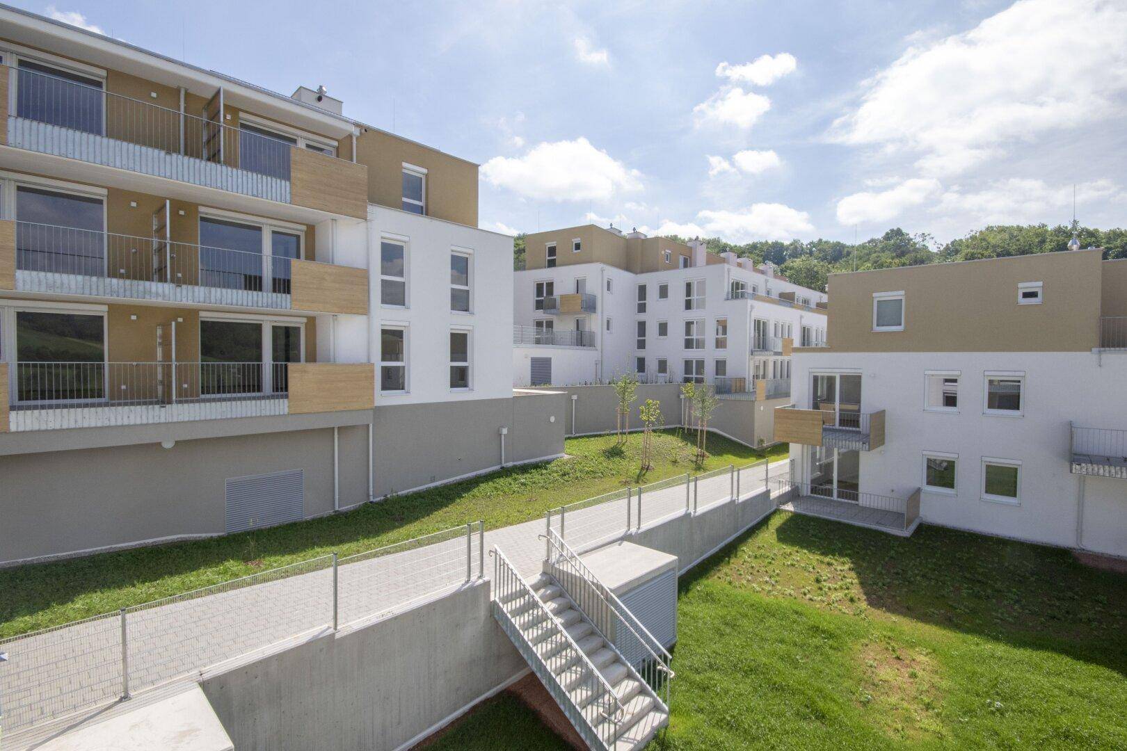 Neubauwohnanlage mit modernen Fassaden und gepflegten Grünflächen in Hanglage.