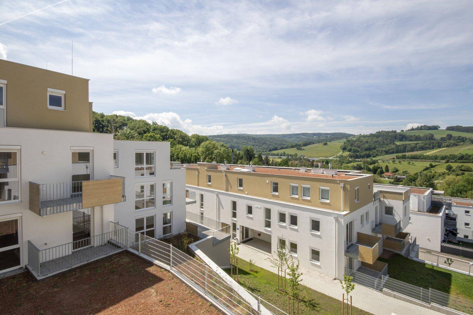 Moderne Wohngebäude in einer grünen Hügellandschaft mit weitem Blick.