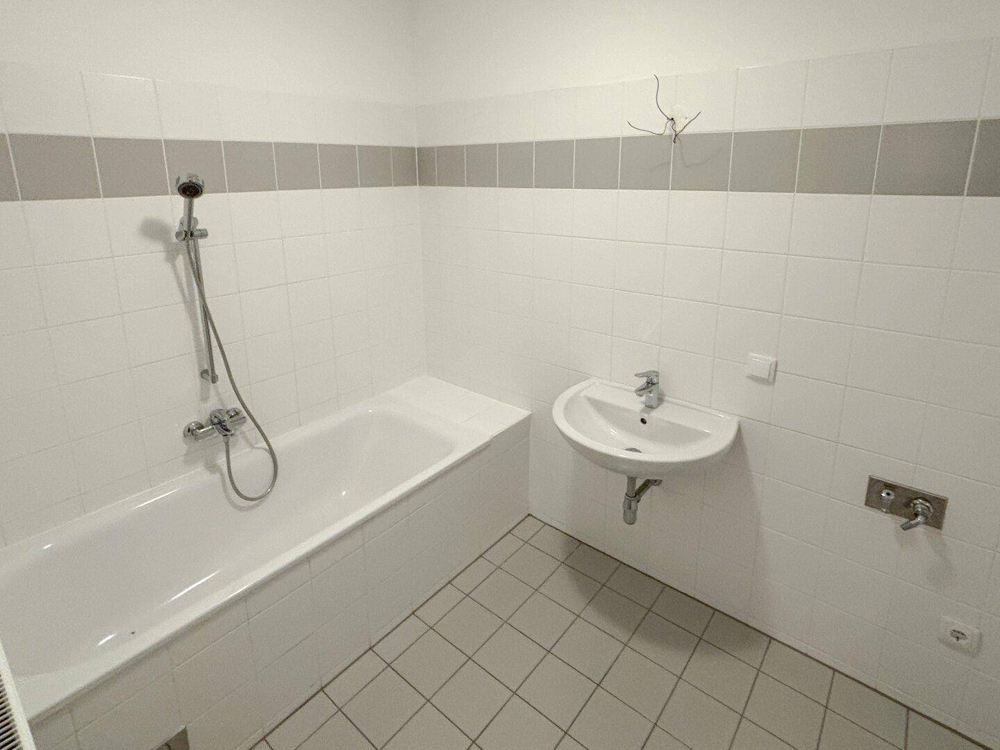 Funktionales Badezimmer mit Badewanne, Duschfunktion und einem einzelnen Waschbecken.