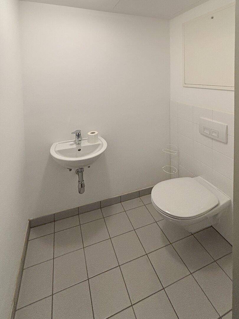 Kompaktes Gäste-WC mit wandhängender Toilette und kleinem Waschbecken, praktisch und sauber.