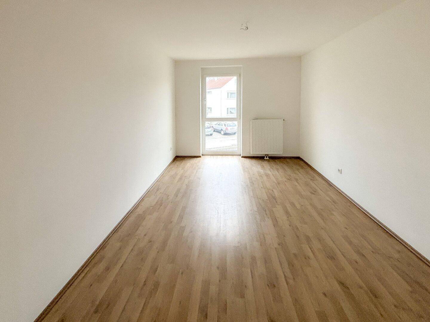 Geräumiges, helles Zimmer mit Laminatboden und großem Fenster, bereit zur individuellen Gestaltung.