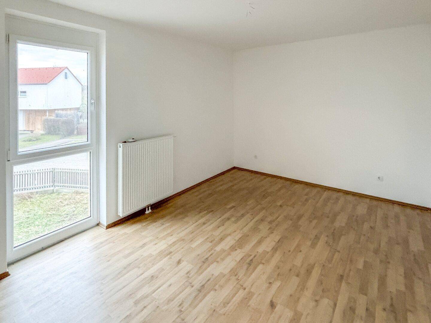 Helles Zimmer mit Laminatboden und Zugang nach draußen, ideal für verschiedene Nutzungen.