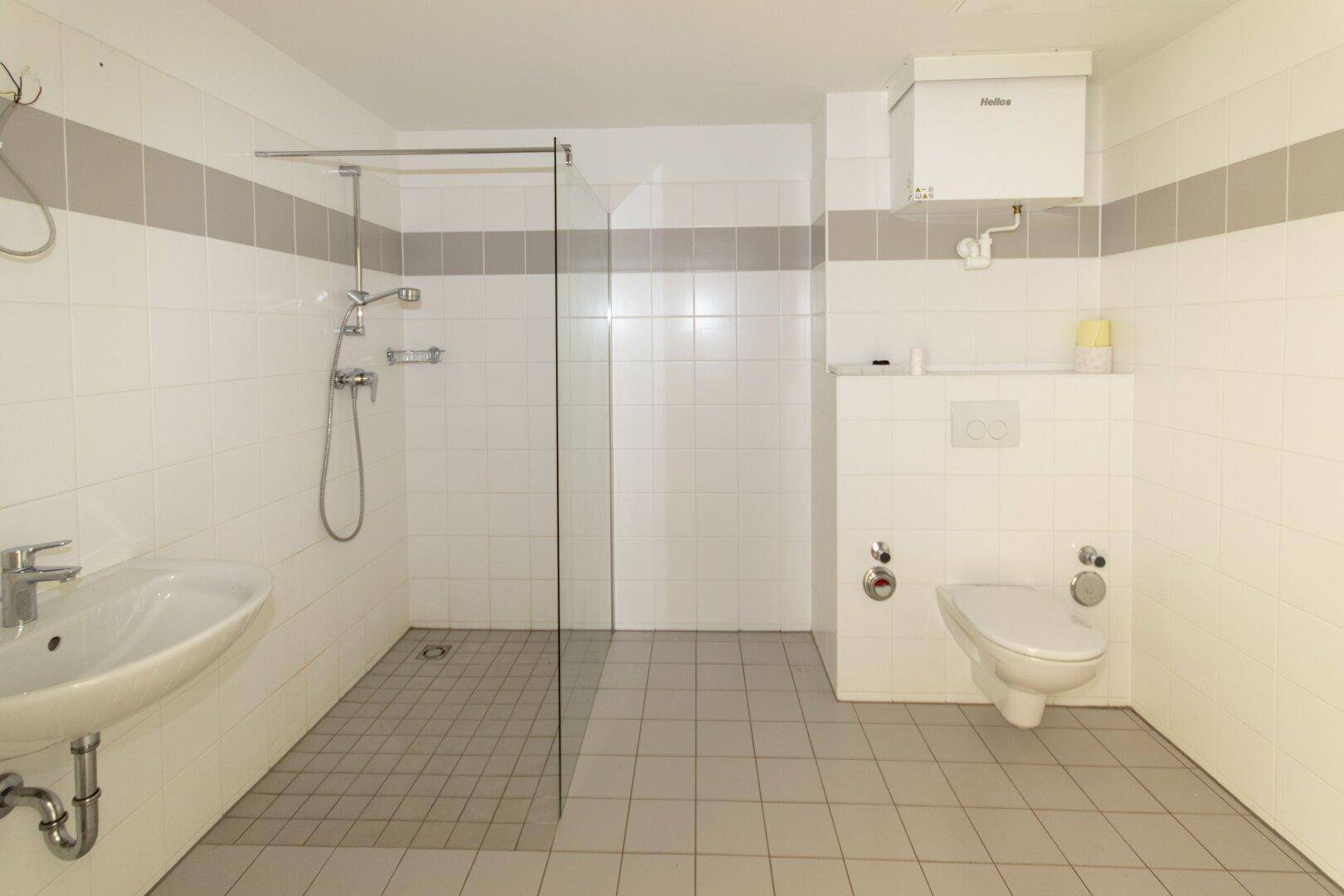 Modernes Badezimmer mit ebenerdiger Dusche, WC und Waschbecken.
