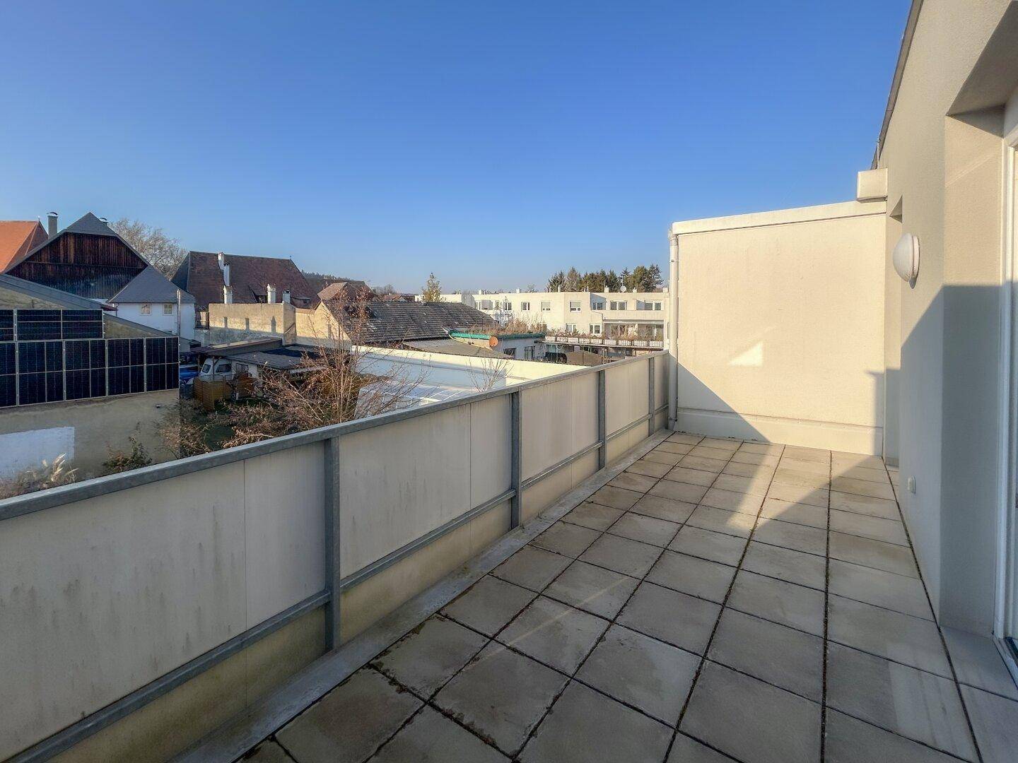 Geräumige Terrasse mit Fliesenboden und Blick auf die umliegende Wohnbebauung.