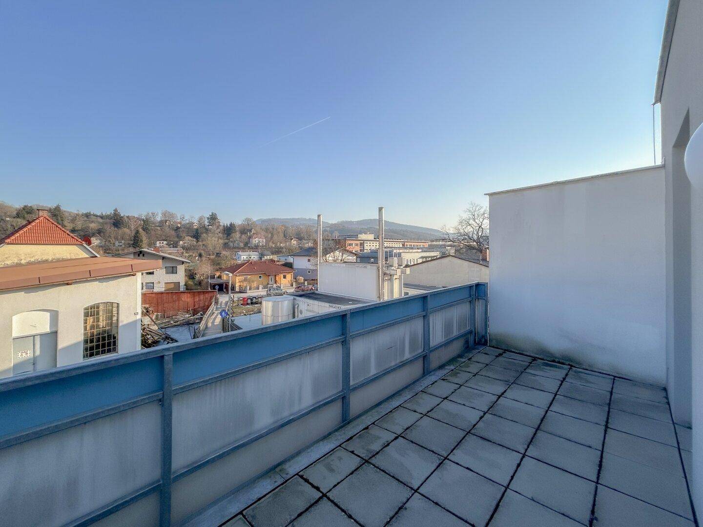 Weitläufige Terrasse mit Fliesenboden und Panoramablick über die Stadt und die Hügel.