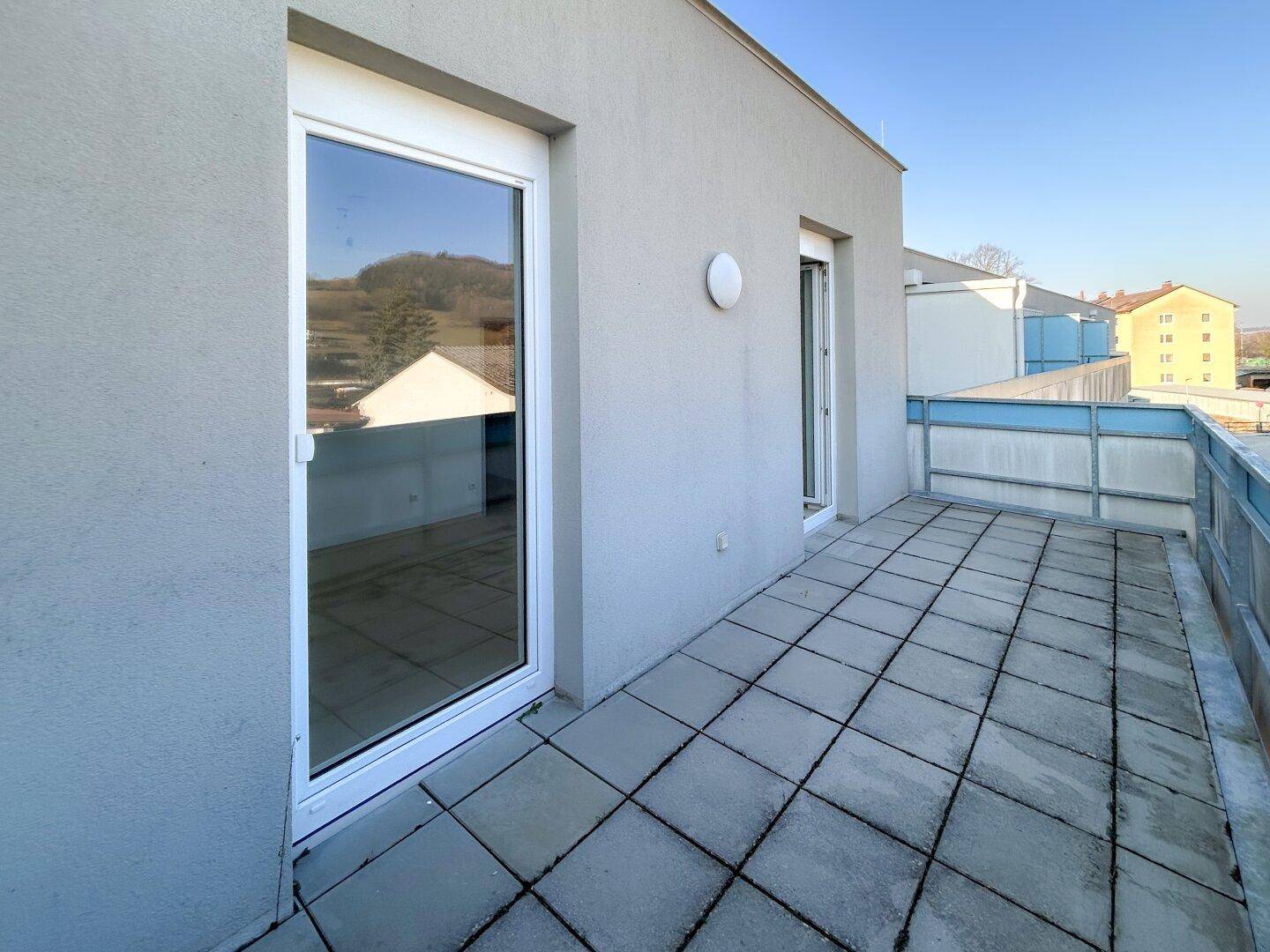 Sonnige Terrasse mit Fliesenboden und direktem Zugang zu den Innenräumen, ideal für Entspannung.