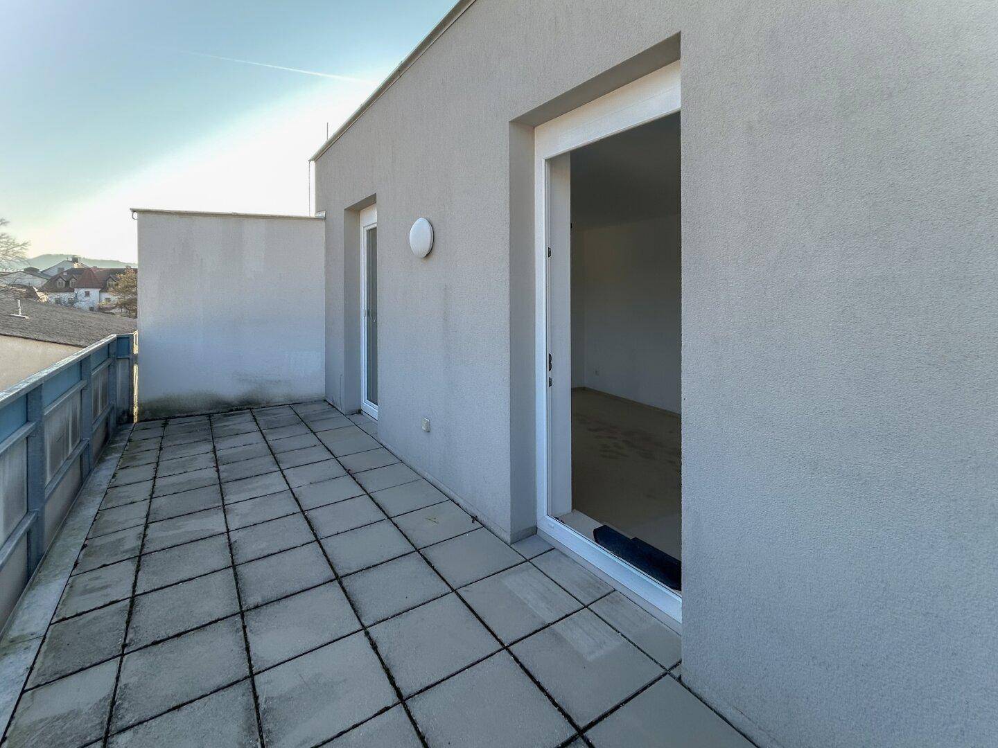 Geräumige Terrasse mit Fliesenboden und Blick auf die Umgebung, bietet viel Platz im Freien.