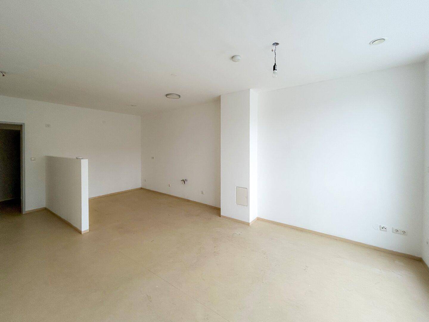 Geräumiger, heller Wohnbereich mit schlichten Wänden und viel Potenzial für moderne Einrichtung.