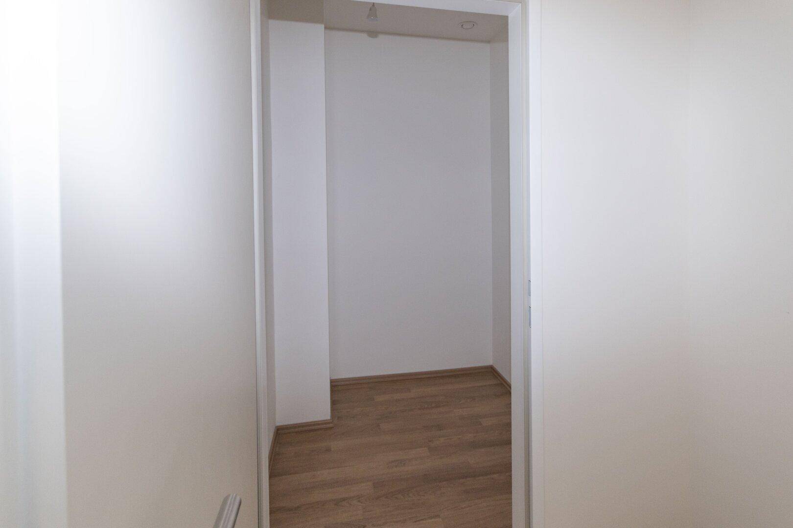 Kleiner, leerer Abstellraum mit Laminatboden und weißen Wänden, ideal für zusätzlichen Stauraum.
