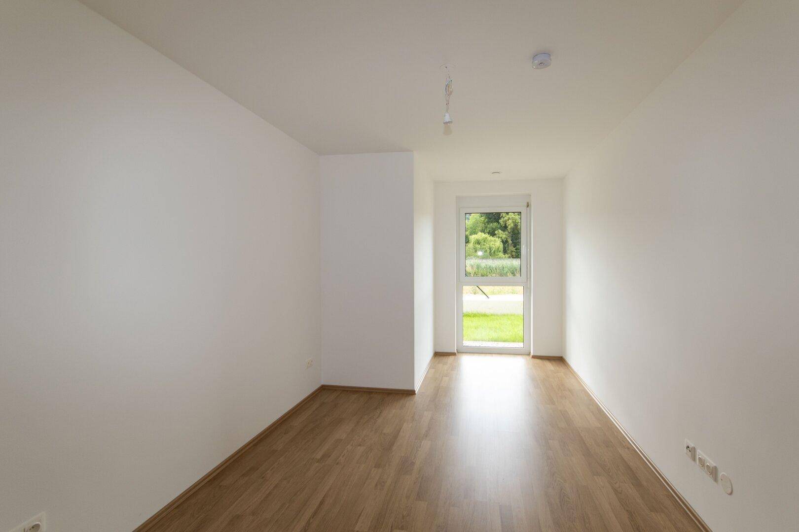 Lichtdurchfluteter Raum mit Laminatboden und Zugang zum Außenbereich, ideal als Wohnzimmer.