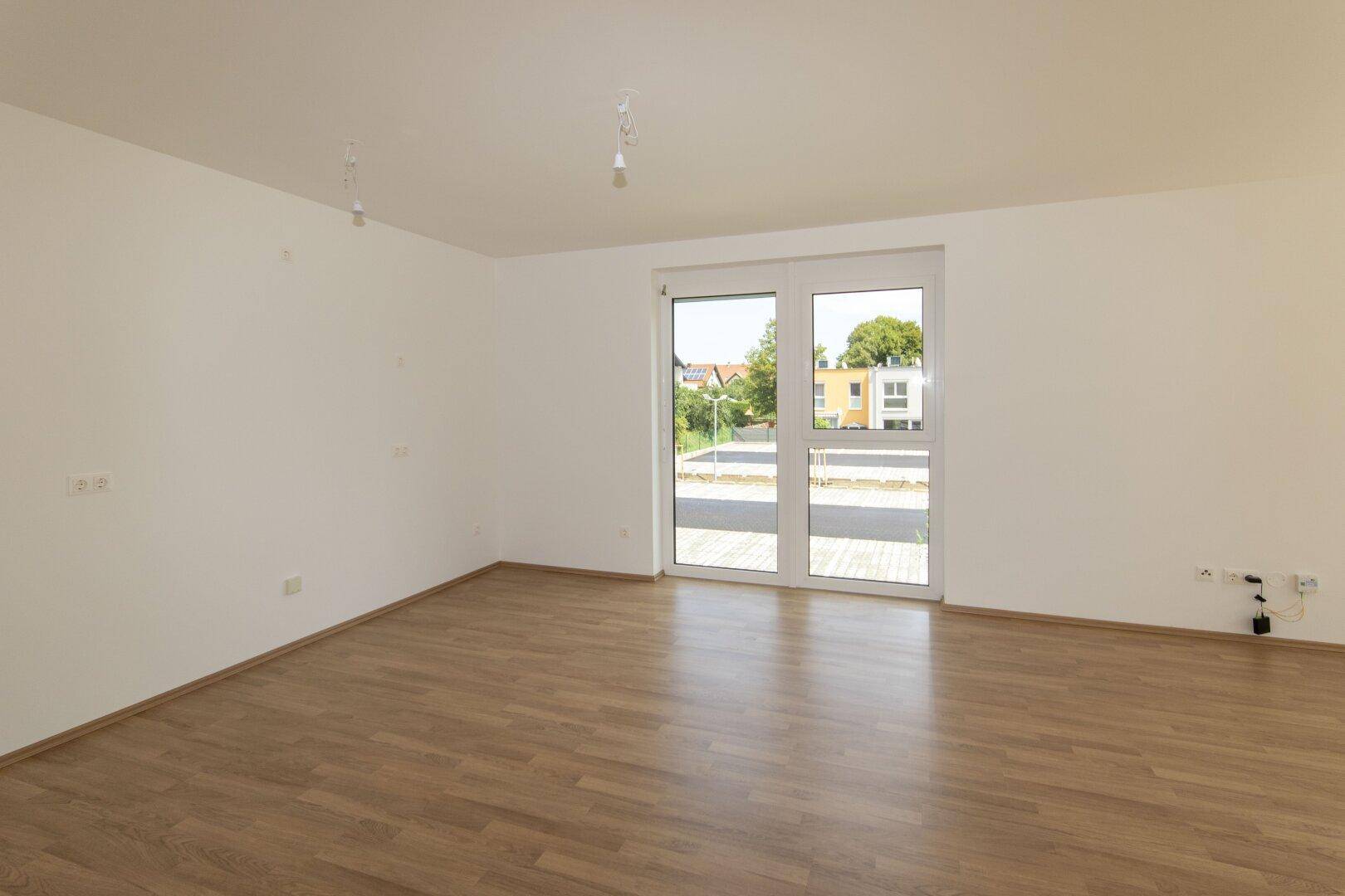 Geräumiges, unmöbliertes Zimmer mit Laminatboden und Zugang zu einem Außenbereich.