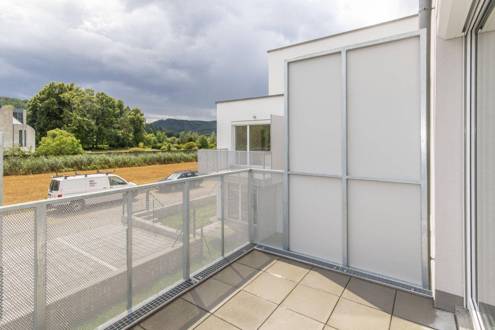 Moderner Balkon mit perforiertem Metallgeländer und Blick auf die umliegende Landschaft.