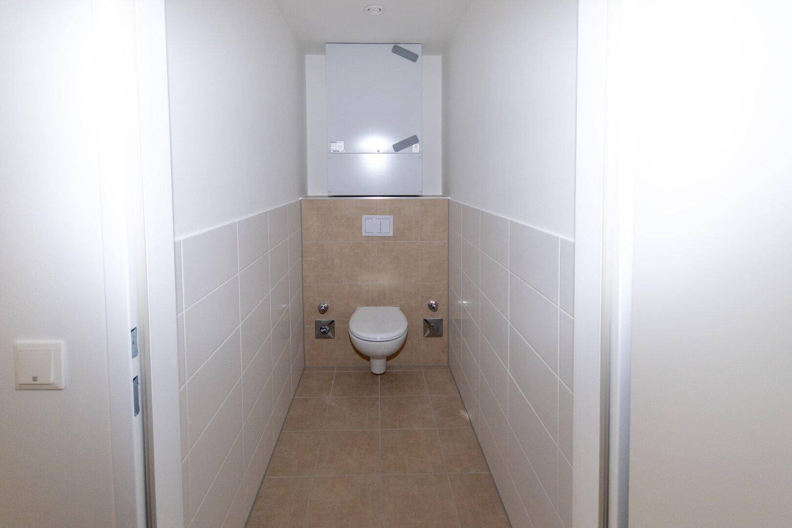 Separates WC mit wandhängender Toilette, gefliest in Weiß und Beige, bietet Funktionalität und Sauberkeit.
