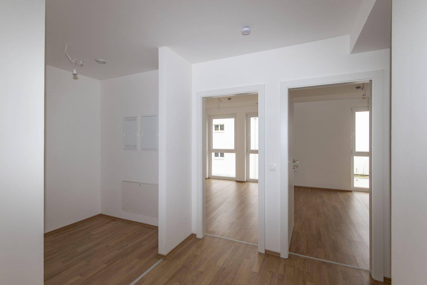 Geräumiger Flur mit Laminatboden und Zugang zu mehreren hellen Zimmern der Wohnung.