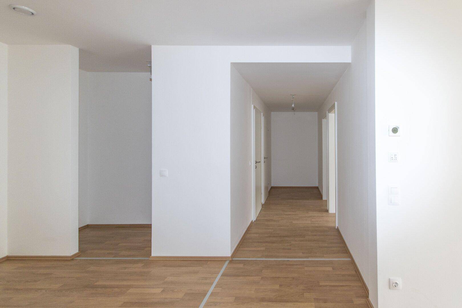 Heller Flur mit Laminatboden und mehreren Türen, der zu verschiedenen Räumen führt.