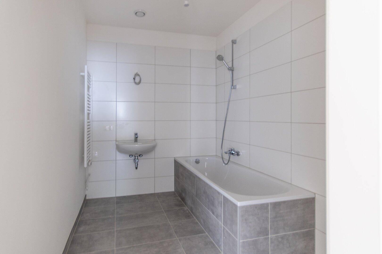 Modernes Badezimmer mit Badewanne, Waschbecken und weißen Fliesen an den Wänden.