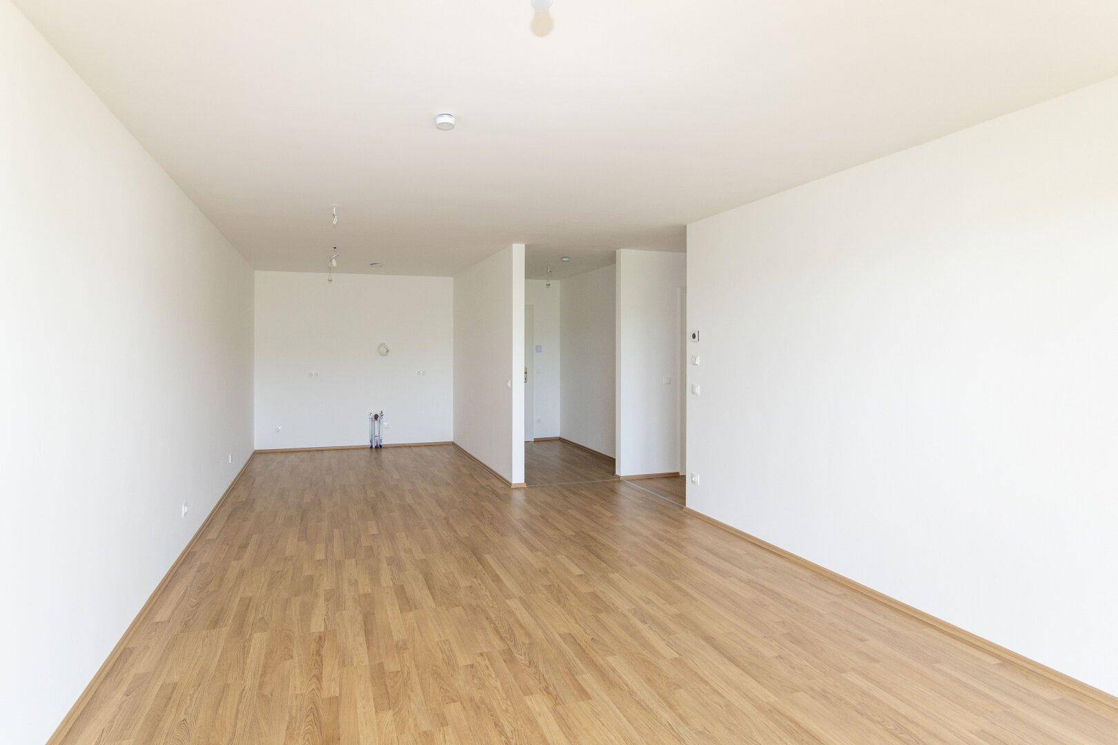 Heller, leerer Raum mit Holzboden und weißen Wänden, bereit für individuelle Gestaltung.