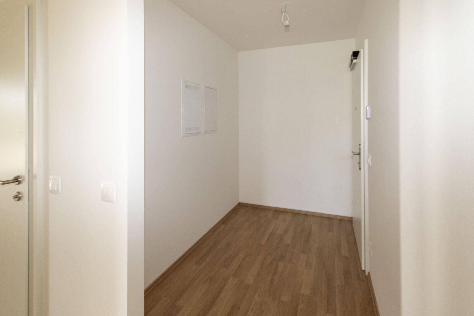 Eingangsbereich mit hellem Laminatboden und weißen Wänden, einladend und funktional.