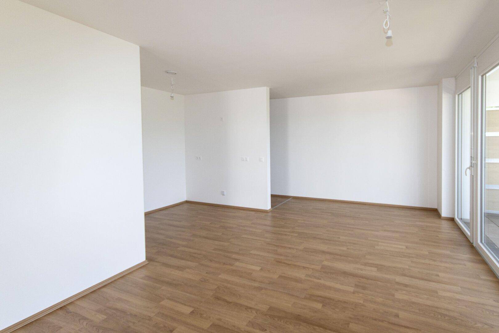 Heller, leerer Raum mit Laminatboden und weißen Wänden, ideal für individuelle Gestaltung.