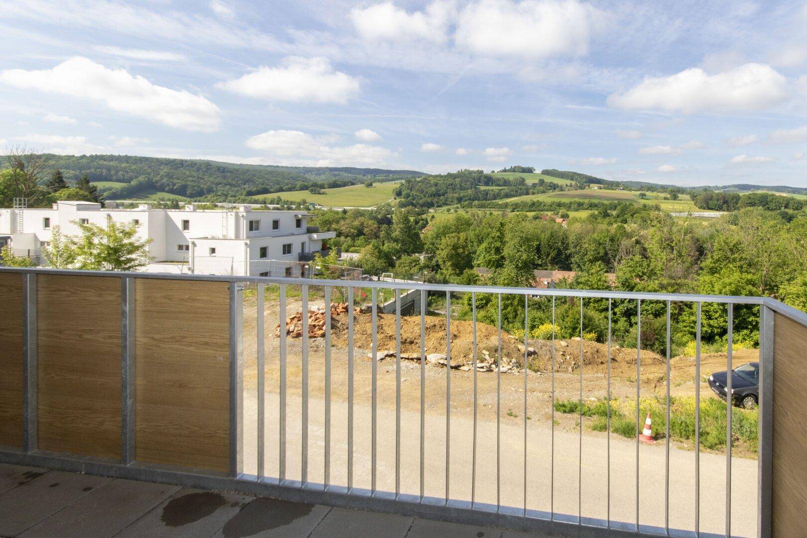 Balkon mit Blick auf die umliegende Natur und eine Baustelle im Vordergrund.