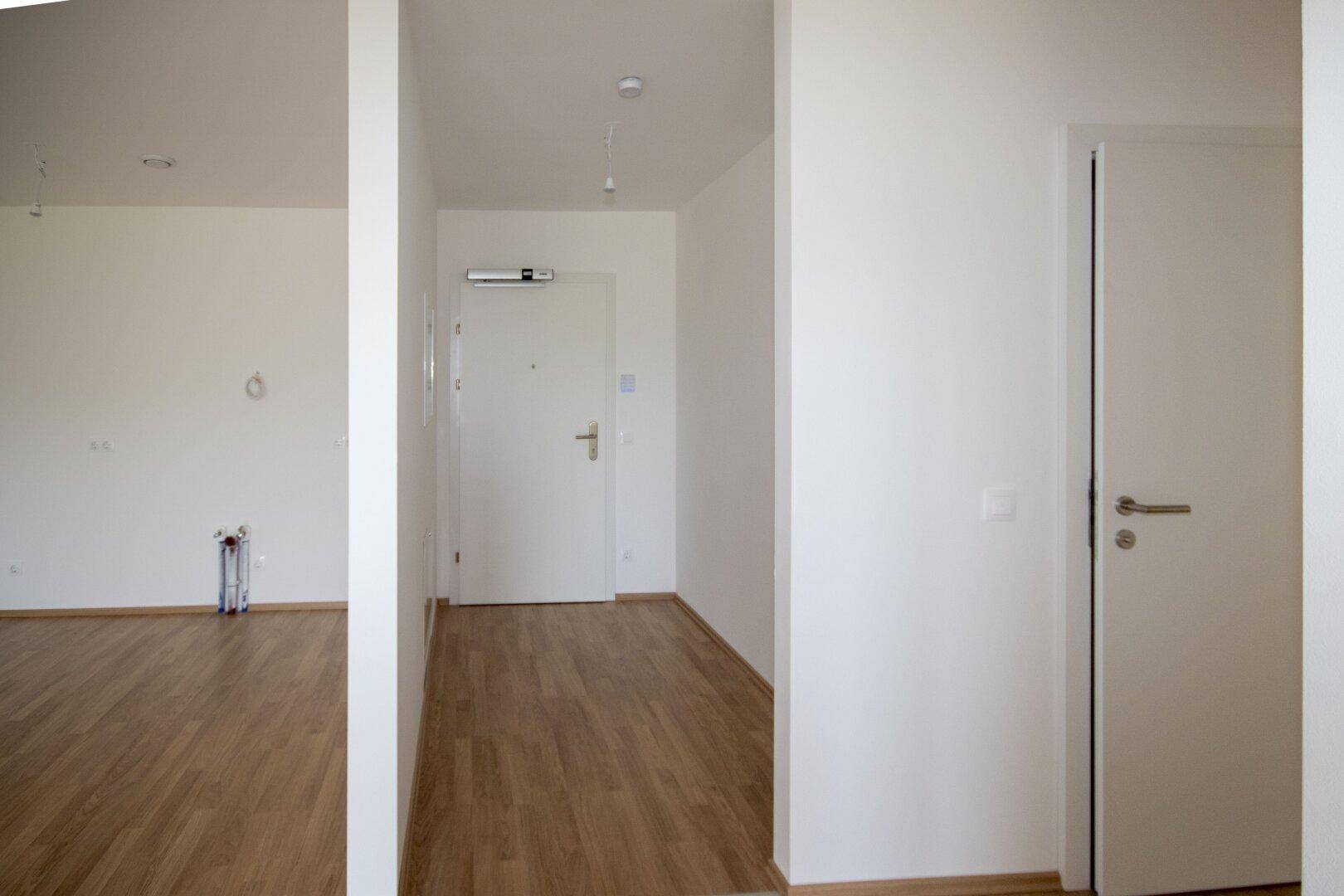 Heller Flur mit Laminatboden und weißen Türen, der zu den verschiedenen Räumen führt.