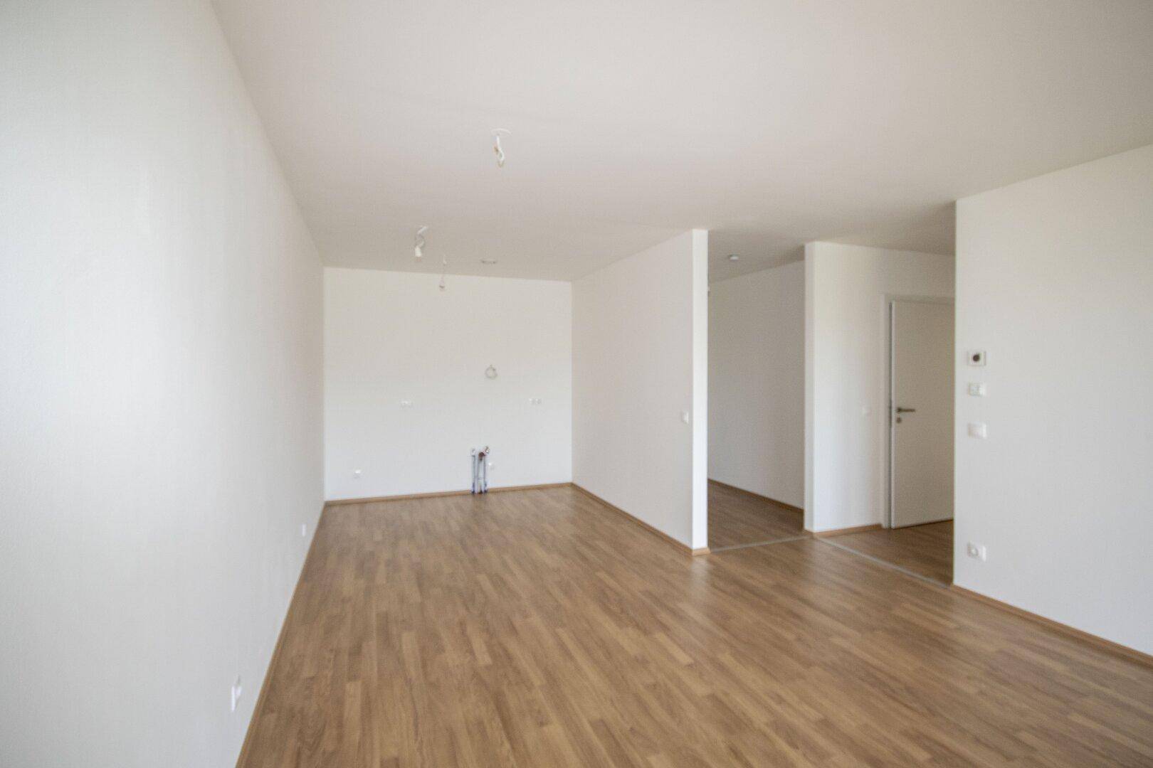Geräumiger, heller Raum mit Laminatboden und weißen Wänden, bereit für die individuelle Gestaltung.