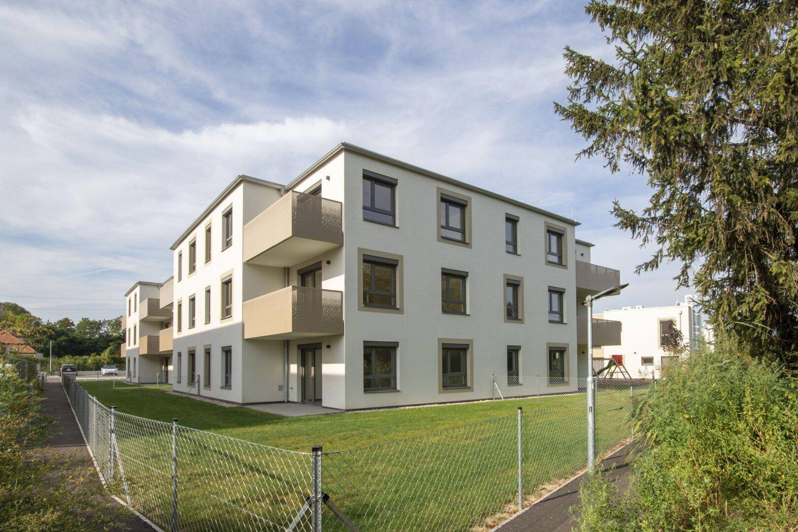 Neubau-Wohngebäude mit schlichter Architektur, Balkonen und umgebenden Grünflächen.