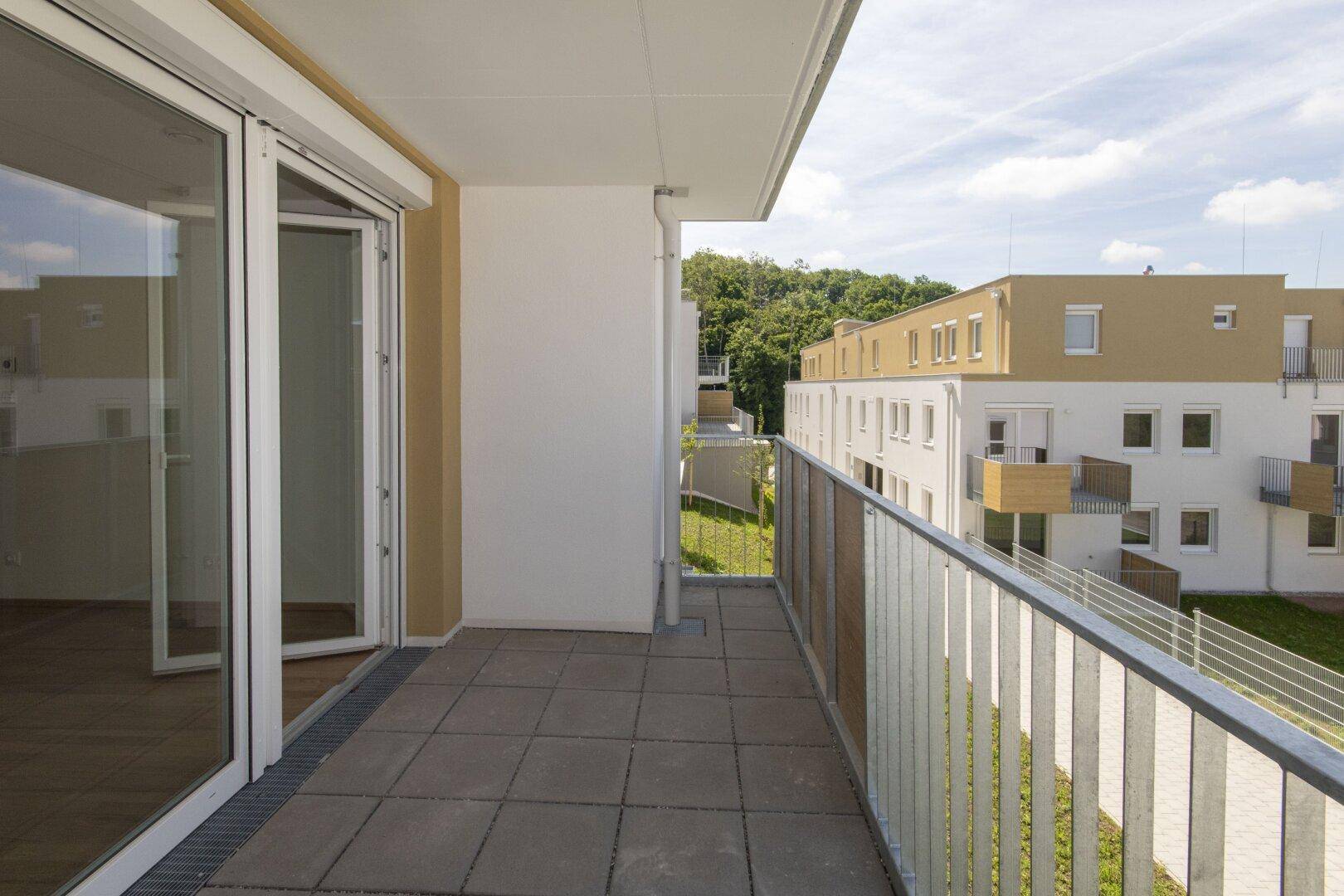 Geräumiger Balkon mit Fliesenboden und Zugang zum hellen Innenbereich der Wohnung.