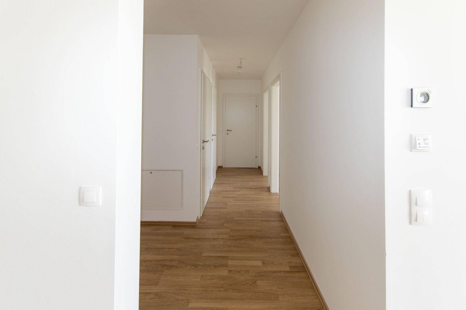 Langer, heller Flur mit Holzboden und mehreren Türen zu den angrenzenden Zimmern.