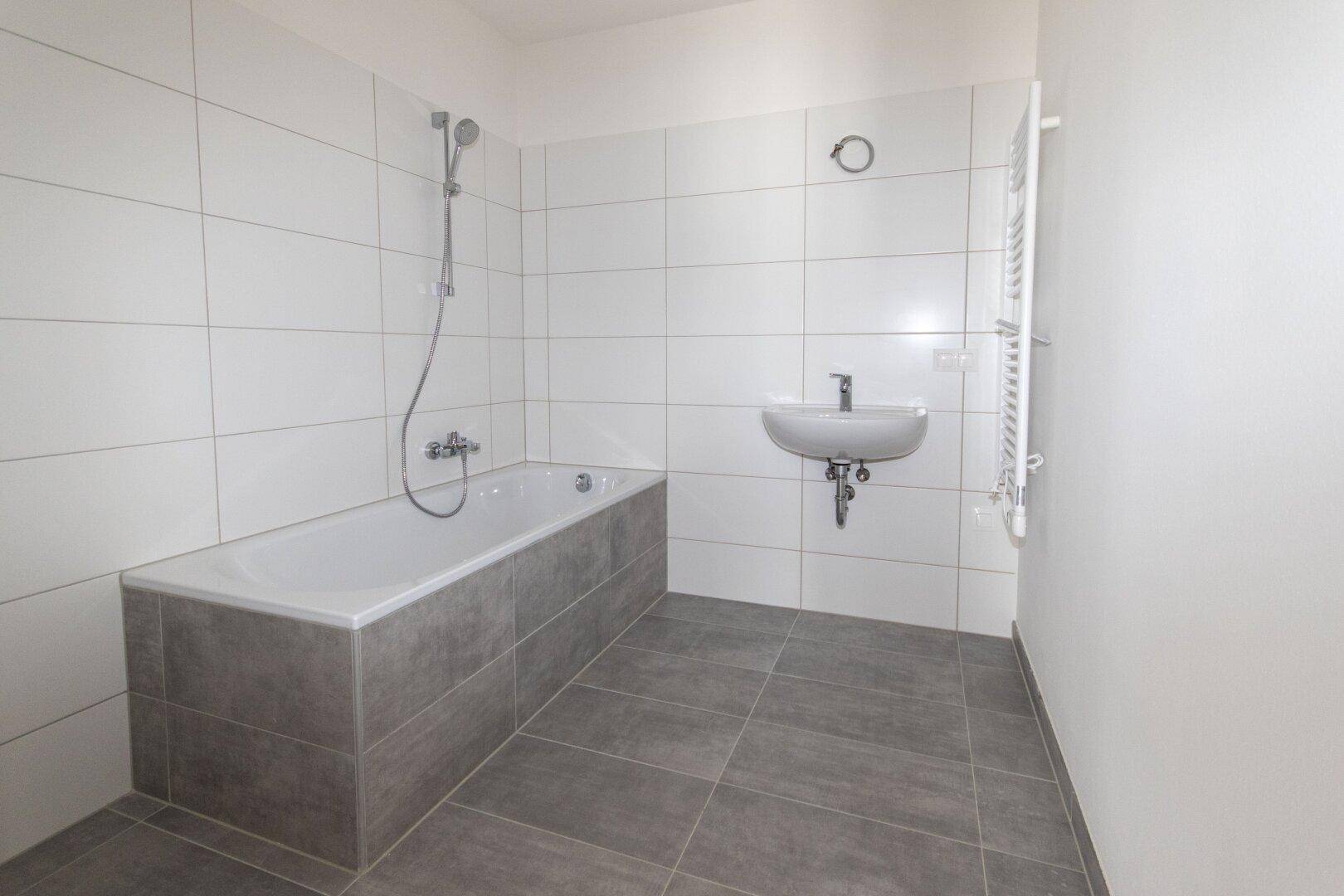 Modernes Badezimmer mit Badewanne, Waschbecken und weißen Fliesen.