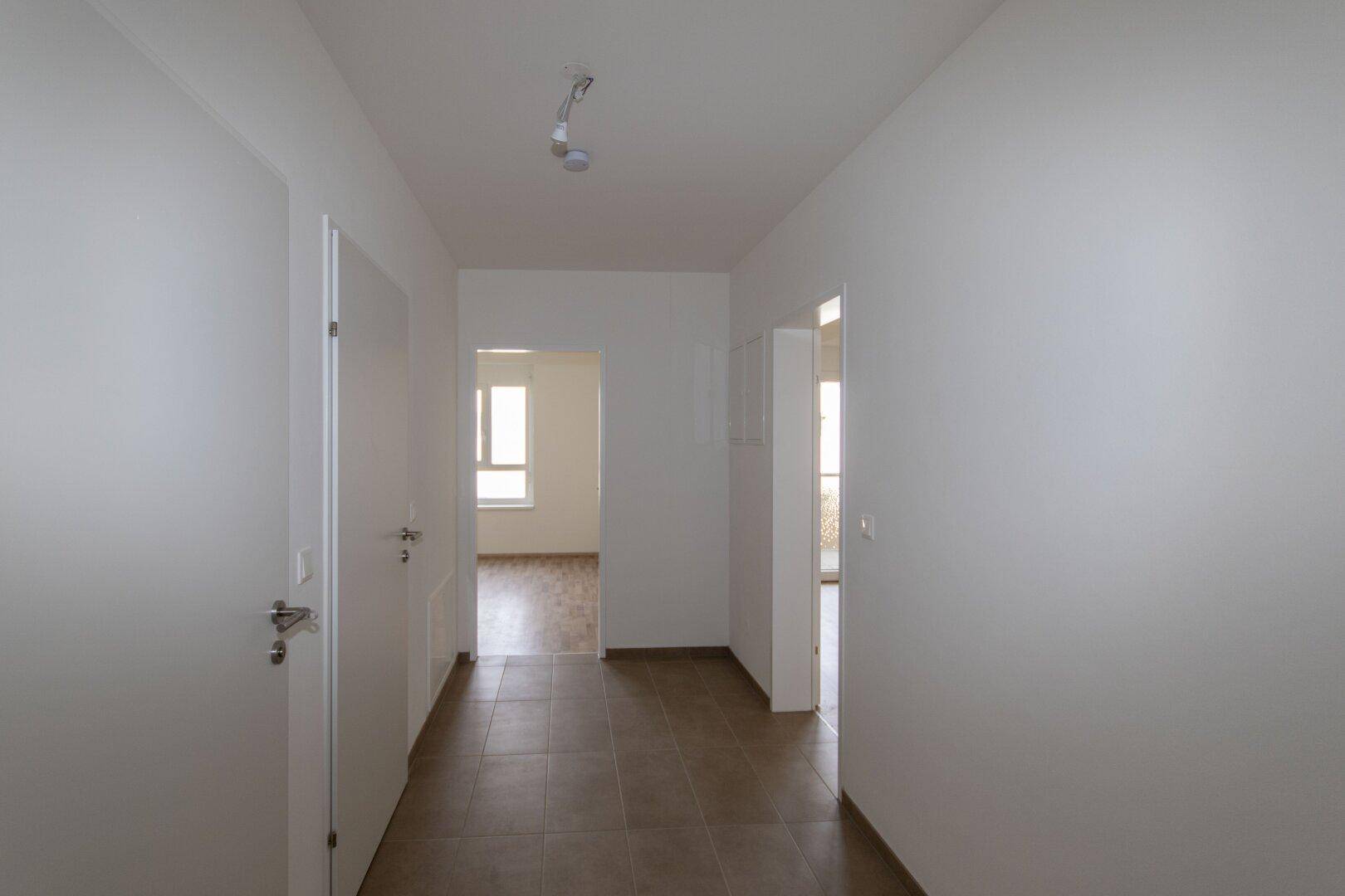 Heller Flur mit Fliesenboden und Zugang zu verschiedenen Räumen der Wohnung.