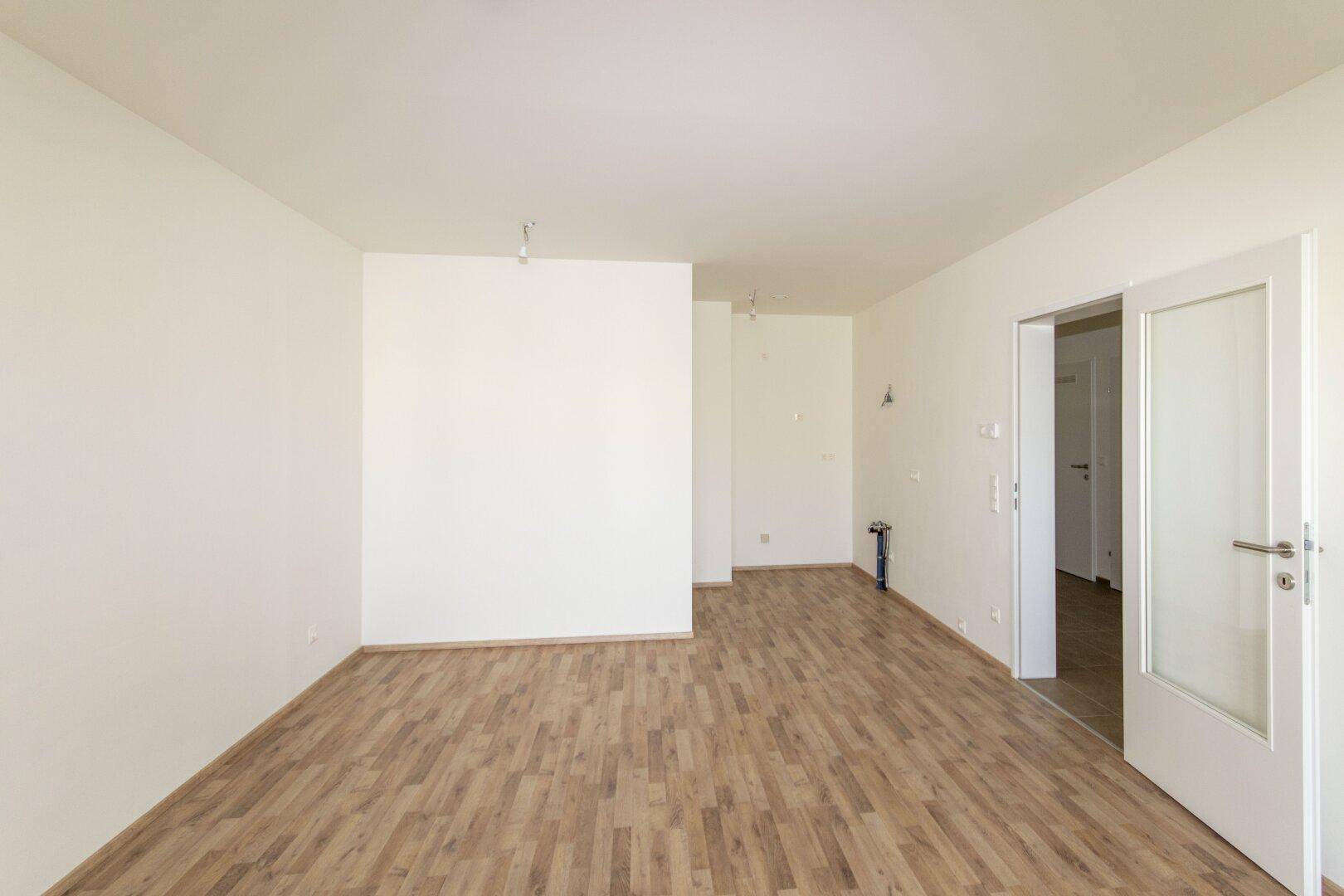 Geräumiger, heller Raum mit Holzboden und weiß gestrichenen Wänden, bereit zum Einzug.