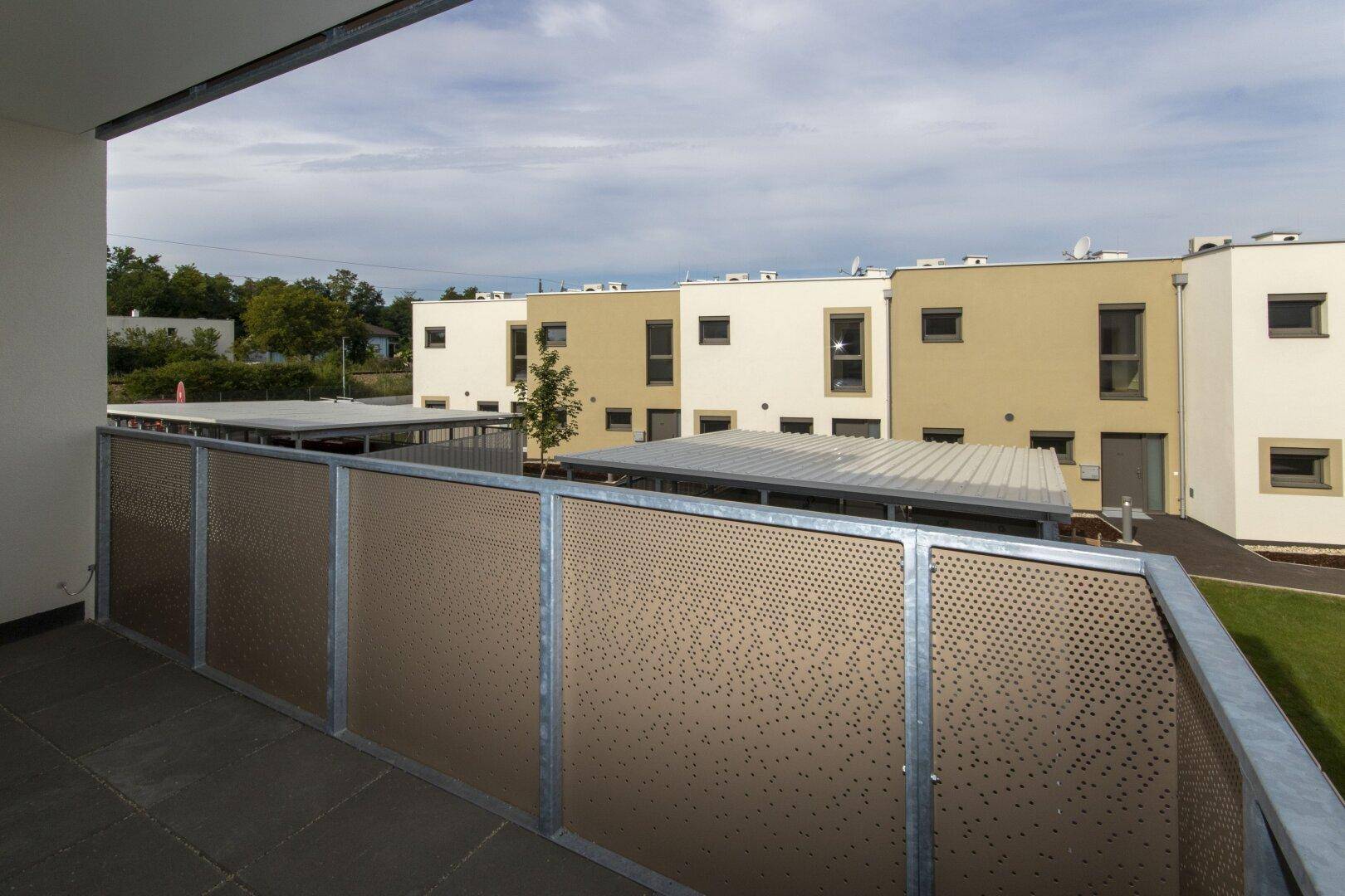 Balkon mit moderner Brüstung und Blick auf die Carports und weitere Wohngebäude.