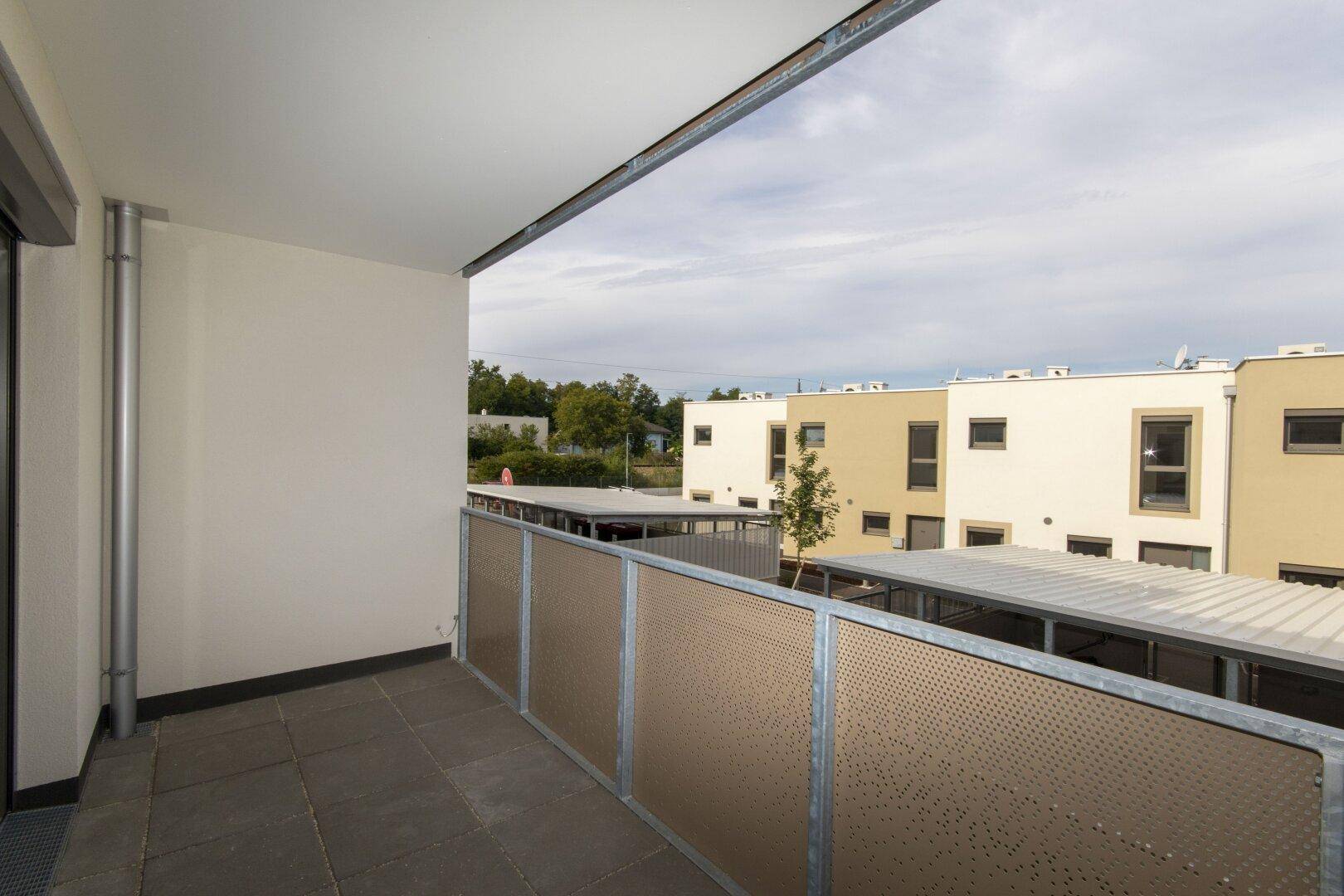 Heller Balkon mit moderner Brüstung und Aussicht auf die Nachbarschaft und Grünflächen.