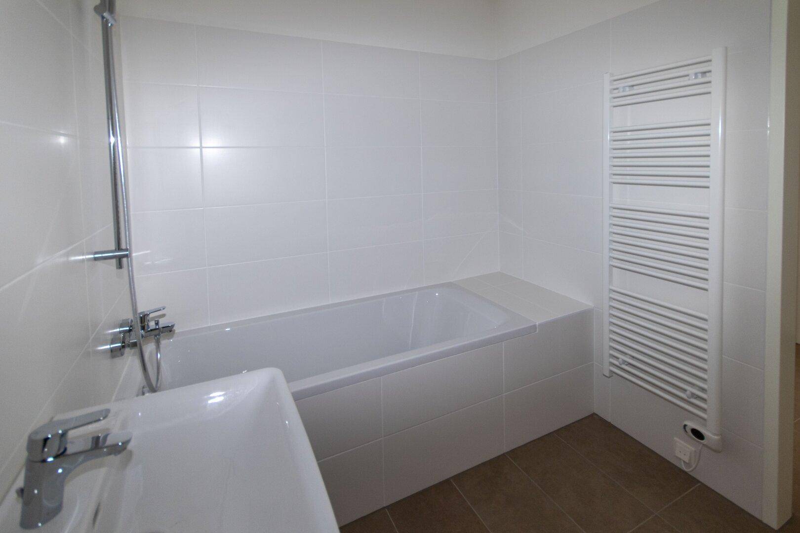 Modernes Badezimmer mit Badewanne, Waschbecken und praktischem Handtuchheizkörper.