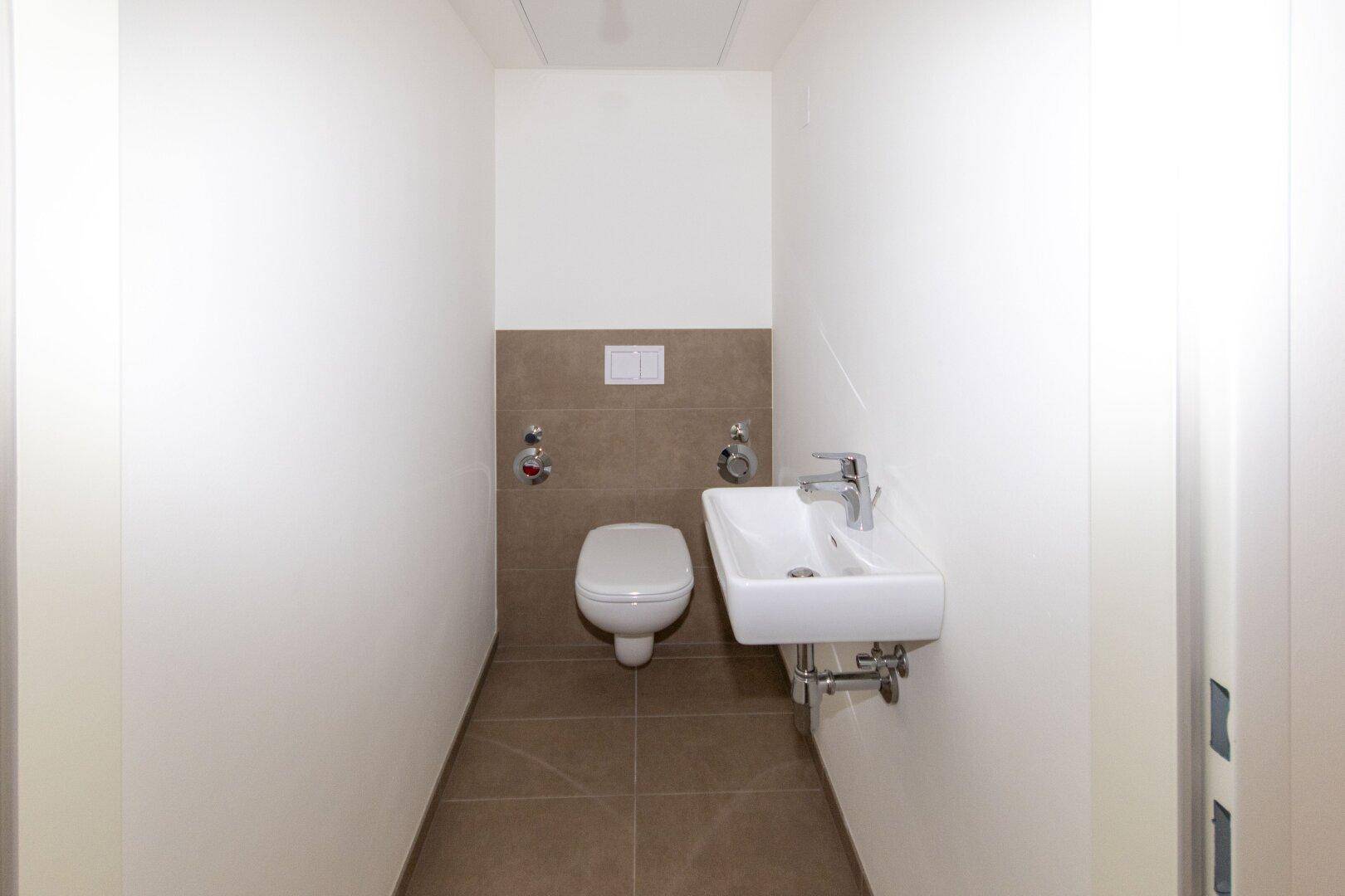 Separates Gäste-WC mit Wand-WC und kleinem Handwaschbecken, ideal für Besucher.
