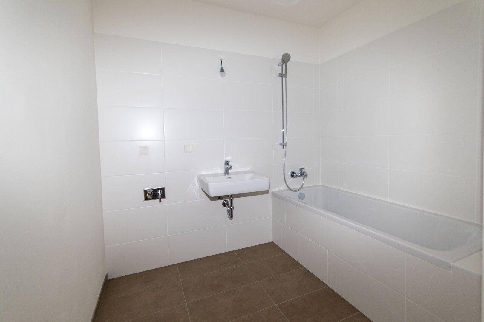 Helles Badezimmer mit Badewanne, Waschbecken und weißen Wandfliesen für eine saubere Optik.