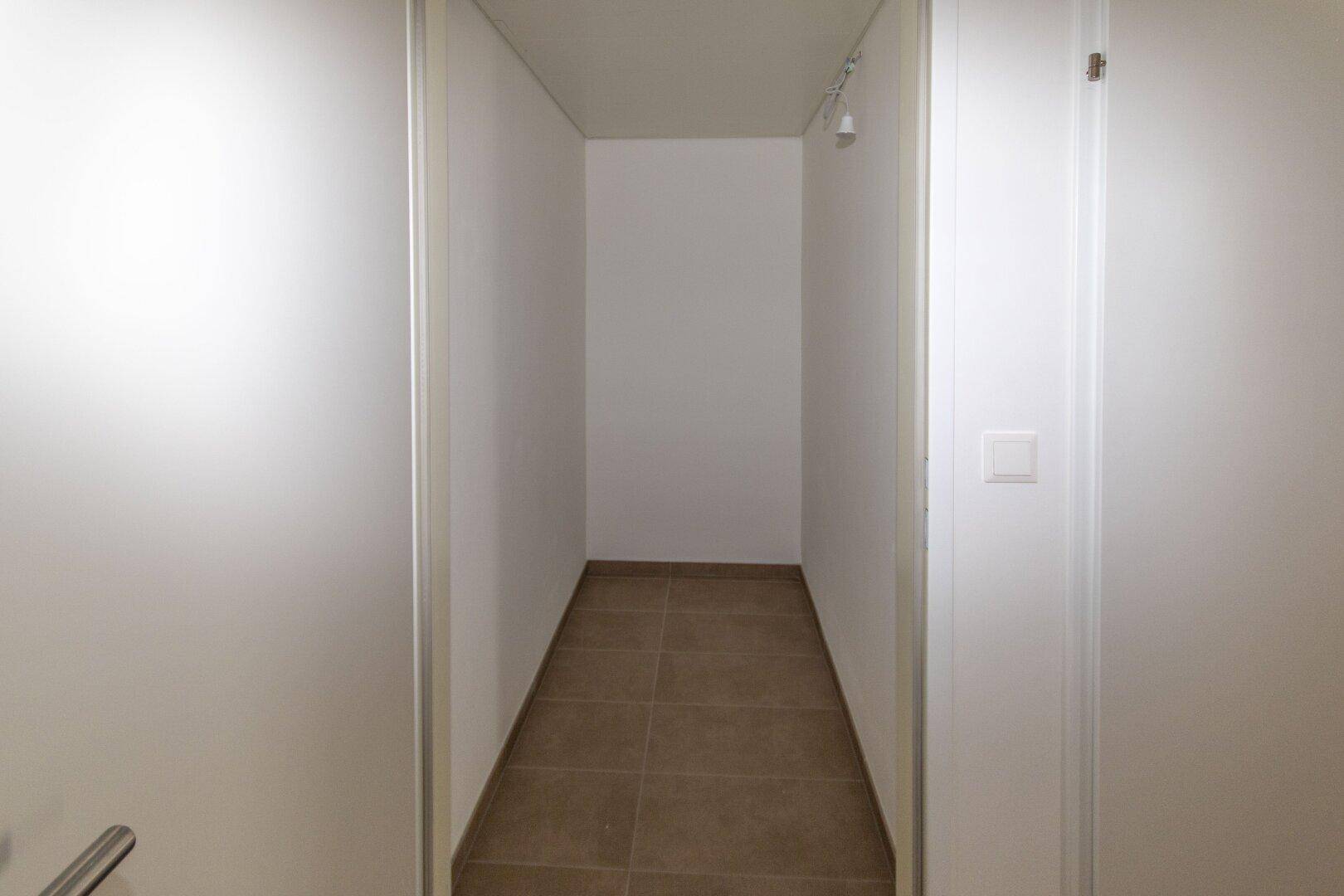 Kleiner Abstellraum mit Fliesenboden und weiß gestrichenen Wänden für zusätzlichen Stauraum.