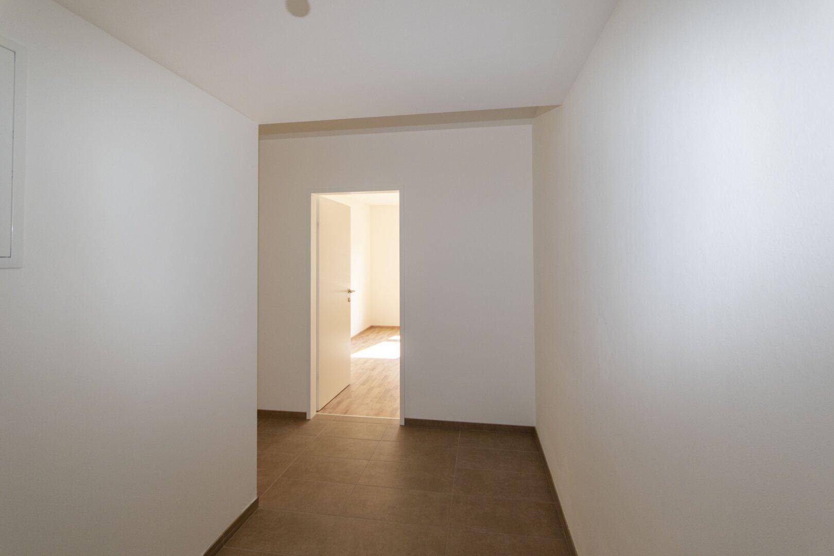 Schmaler Flur mit Fliesenboden, der zu einem weiteren Zimmer führt.