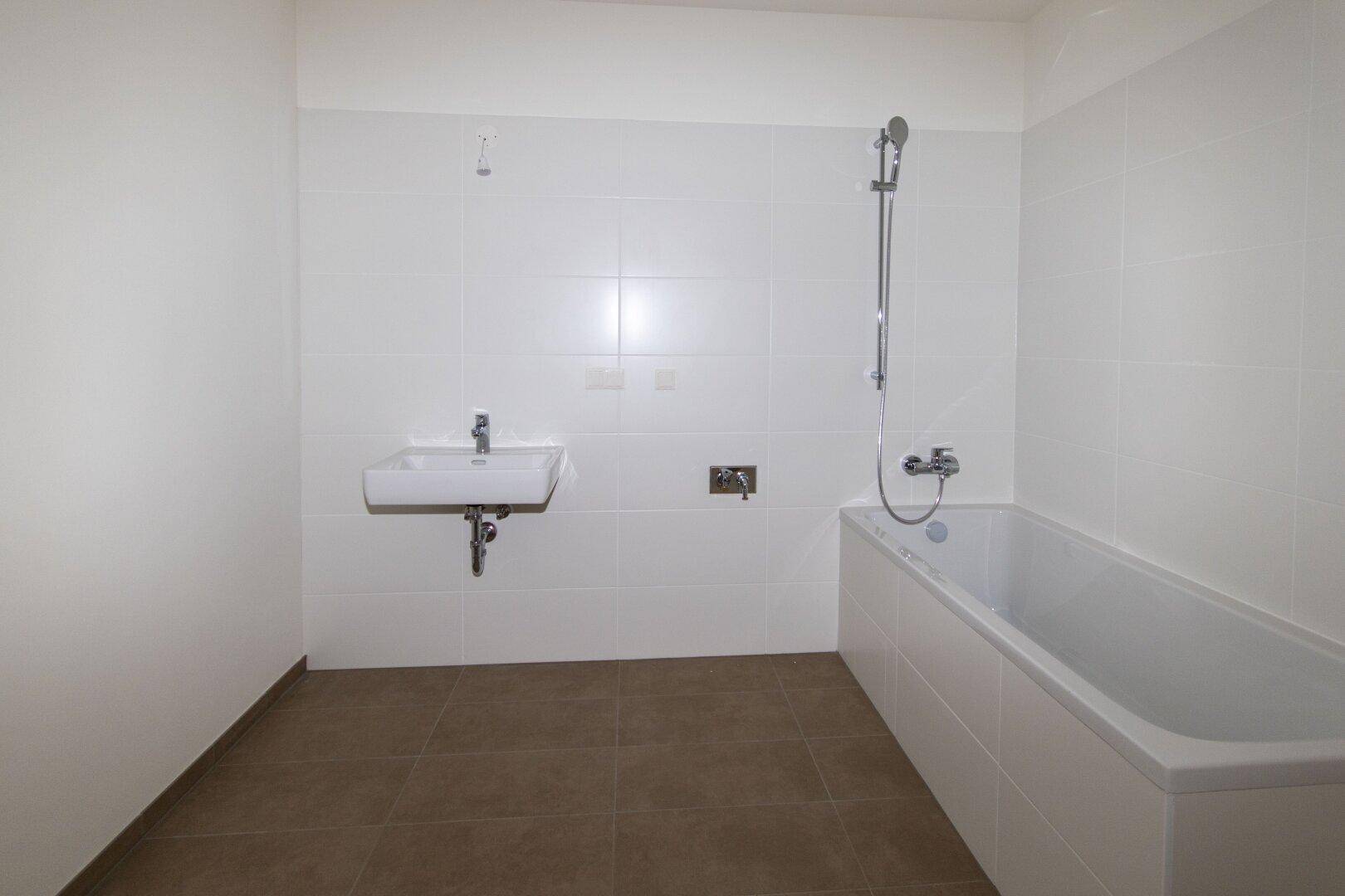 Modernes Badezimmer mit weißen Wandfliesen, Badewanne und Einzelwaschbecken.