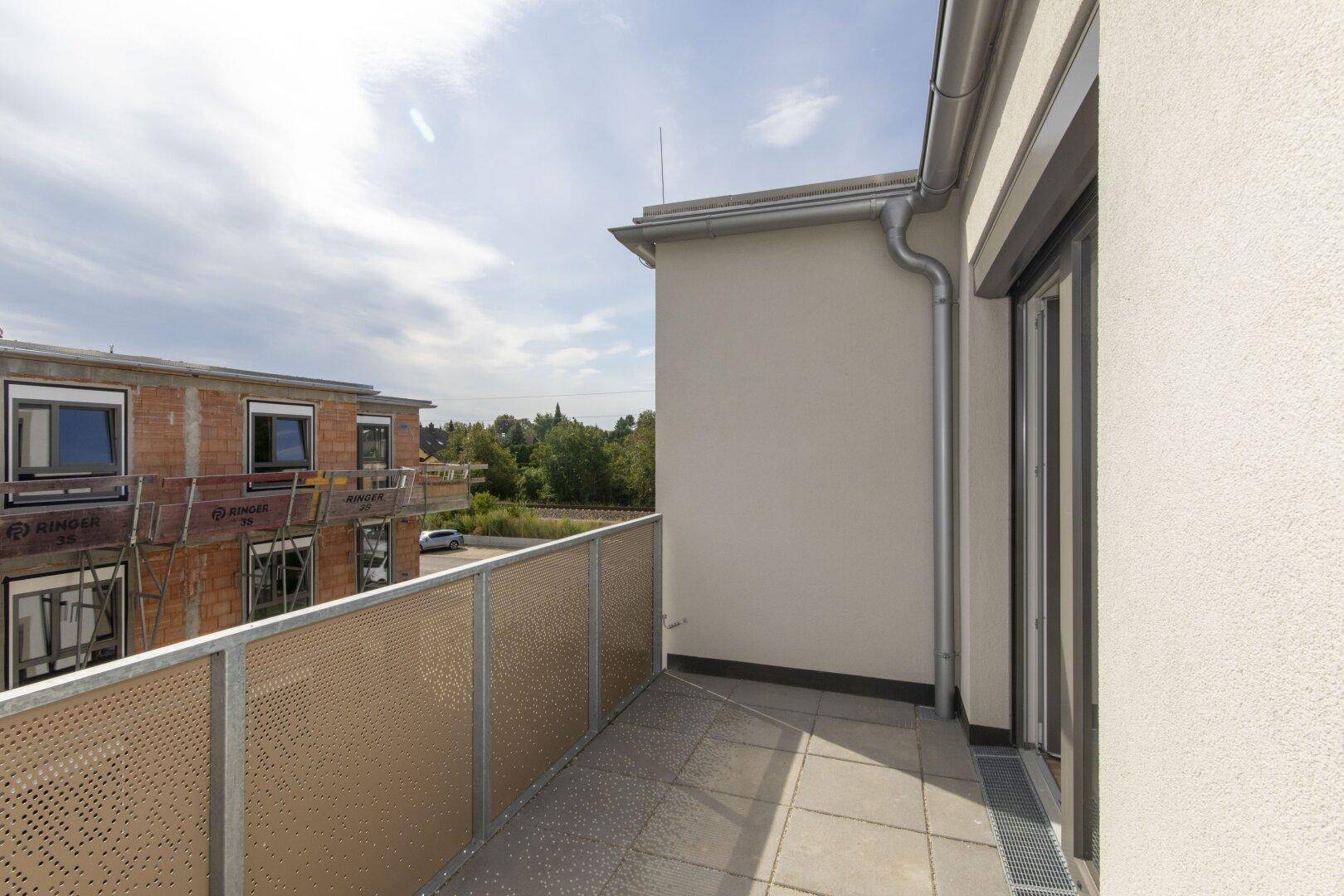 Heller Balkon mit Fliesenboden und moderner Brüstung, ideal für entspannte Stunden im Freien.