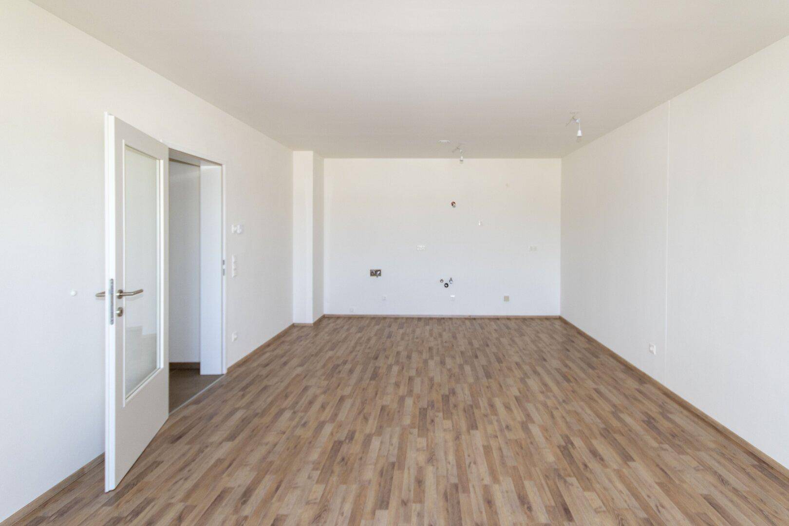 Unmöbliertes Wohnzimmer mit Laminatboden und weißen Wänden, ideal für individuelle Gestaltung.