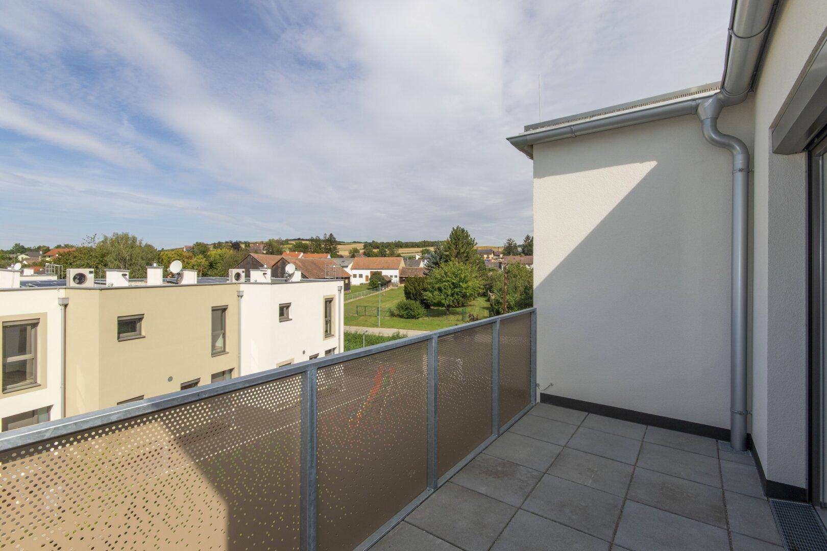 Geräumiger Balkon mit Fliesenboden und weitem Blick über die ländliche Umgebung.