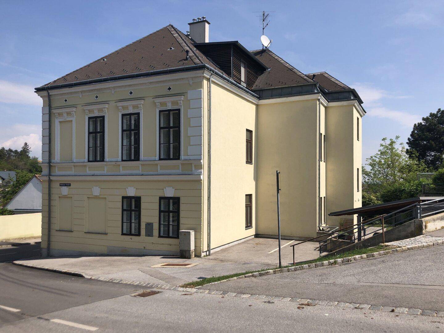 Seitenansicht des Gebäudes mit Parkplatz und barrierefreiem Zugang über eine Rampe.
